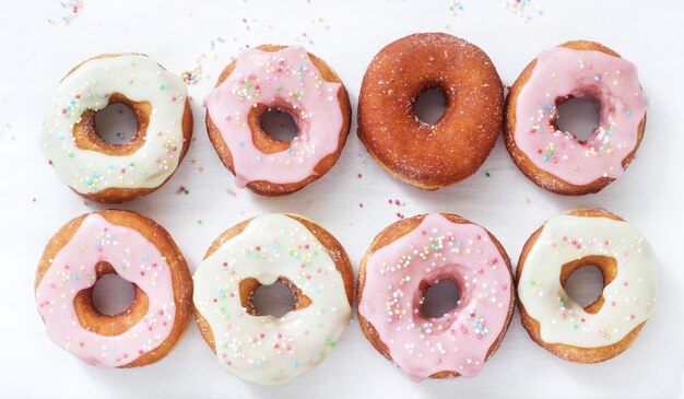 Homemade donuts decorated with colored icing and colored sugar on a light background.