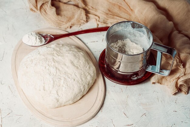 Фото Домашнее тесто для приготовления и выпечки хлеба на фоне белой пшеничной муки в ложке
