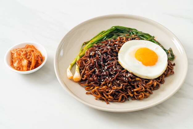 Homemade dried Korean spicy black sauce instant noodles with fried egg and kimchi