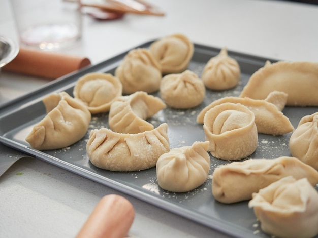 Homemade dumplings of different imperfect and irregular shapes in a tray ready for cooking