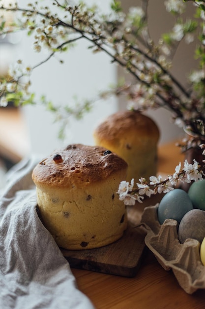 Homemade easter bread natural dyed eggs and spring blossom on rustic table in room Happy Easter