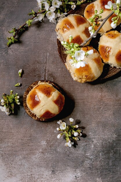 꽃 벚꽃 가지와 세라믹 접시에 만든 부활절 전통적인 뜨거운 십자가 빵