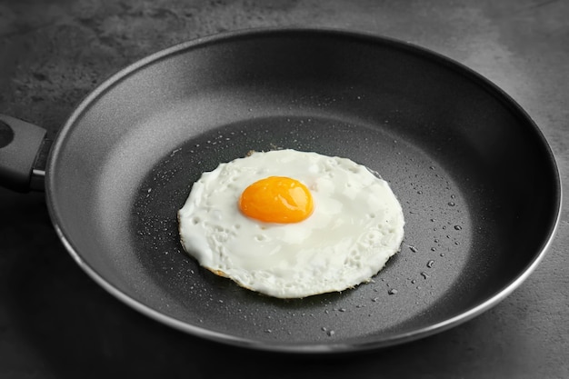 Homemade over easy fried egg in pan on dark background