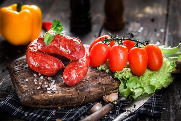 Photo homemade food, sausage large fried in a pan, cherry tomatoes and lettuce, spices, dark and moody