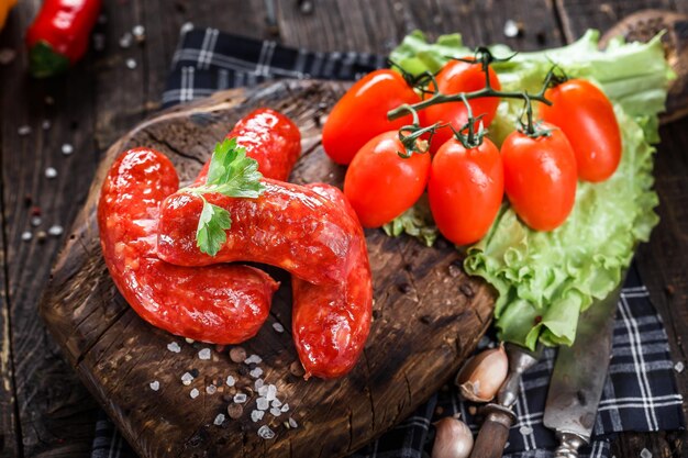 Photo homemade food, sausage large fried in a pan, cherry tomatoes and lettuce, spices, dark and moody