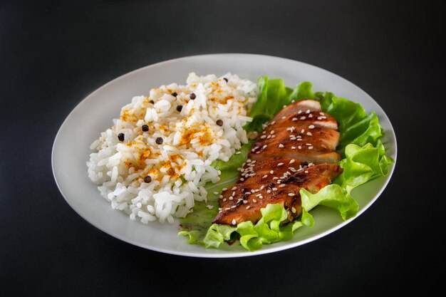 自家製料理-黒地に白ご飯とコショウを添えた照り焼きチキン。