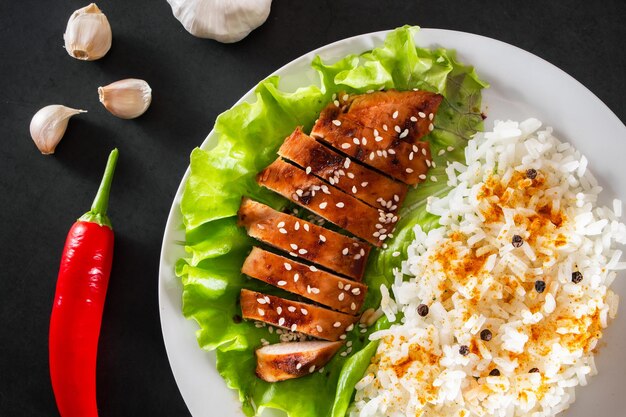 Homemade food teriyaki chicken with white rice and pepper on a black background