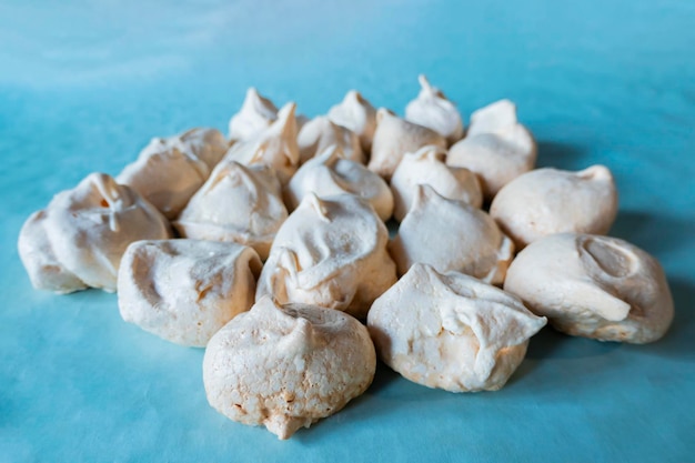 Homemade french milkcolored meringues on blue paper