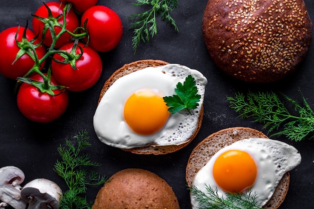 Homemade, fresh, fried chicken eggs with dill, parsley, tomatoes and sesame bun for a healthy breakfast. Top view. Protein food. Eggs sandwiches