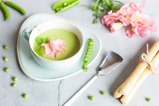 Homemade fresh green pea cream soup with pea sprouts and flowers