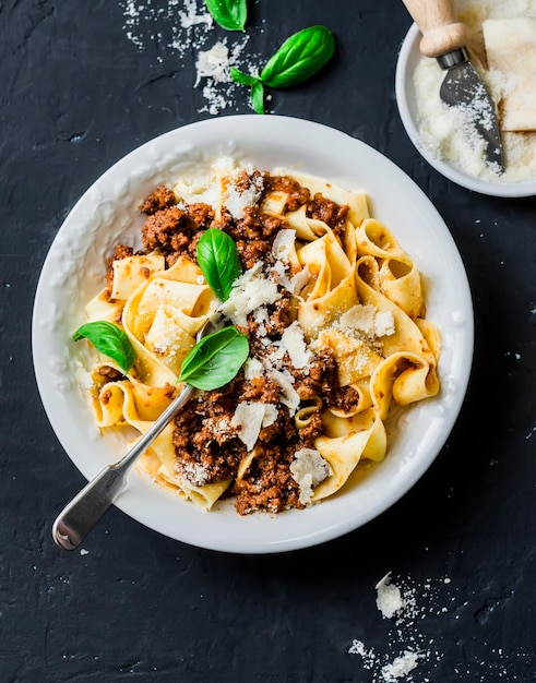 Homemade freshness pappardelle pasta with beef bolognese sauce on a dark background Traditional Italian pasta