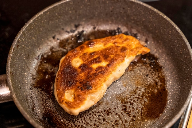 Homemade fried chebureks with meat in a frying pan