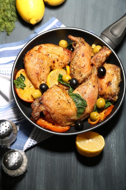 Homemade fried chicken drumsticks with vegetables on pan on wooden background