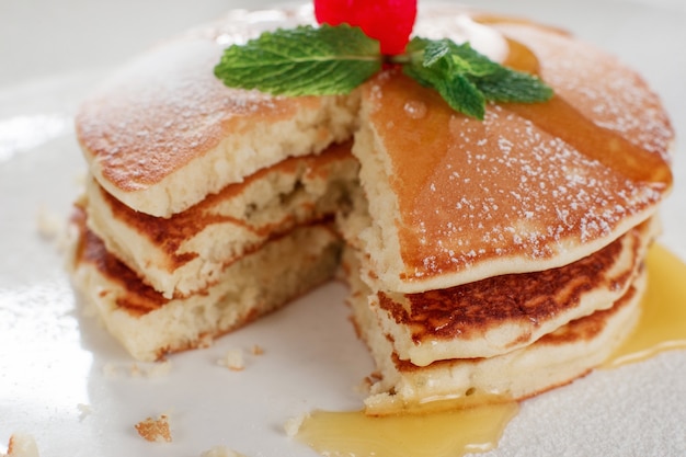 Homemade fried pancakes with hohey closeup. Crepe with cherry on white plate background. Traditional US meal.