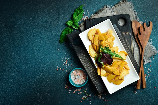 Homemade fried potatoes with garlic on a plate Close up On a dark background