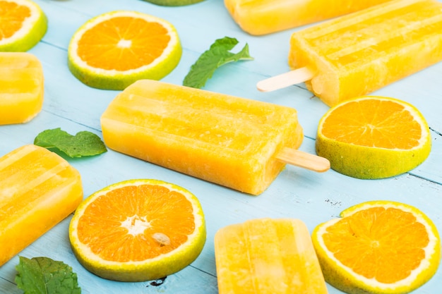 Homemade frosty popsicles with oranges on a blue wooden