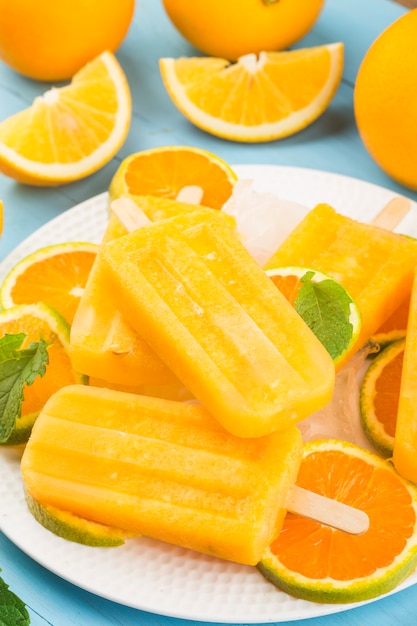 Homemade frosty popsicles with oranges on a blue wooden