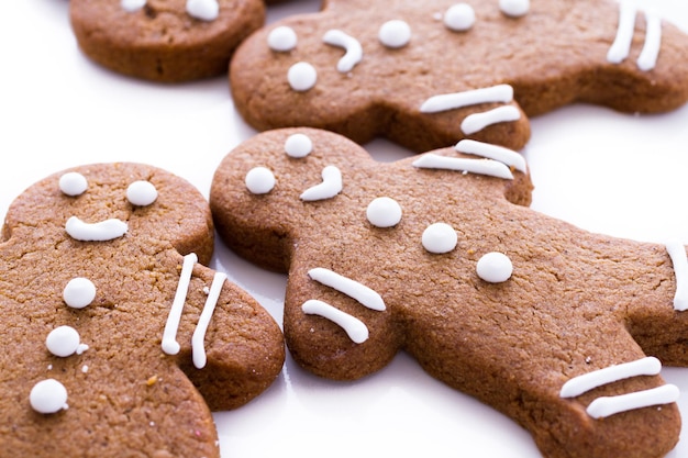 Homemade gingerbread cookies decorated with white icing on white background.