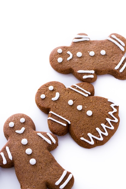 Homemade gingerbread cookies decorated with white icing on white background.