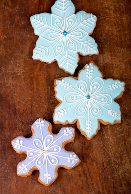 Photo homemade gingerbread cookies, festive christmas and new year sweets in the form of blue snowflakes background card, on a wooden board