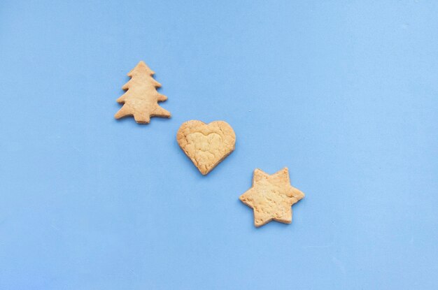 Homemade gingerbread cookies in a variety of shapes, isolated on blue background. Flat lay with Christmas cookies displayed in a circle shape.