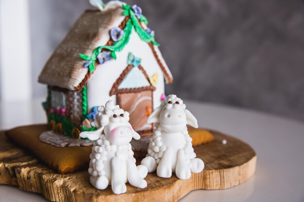 Foto casa di marzapane fatta in casa su piatto di legno con due pecore di marzapane