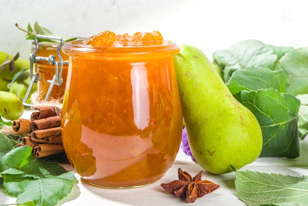 Homemade golden colored pear jam, with farm pears and leaves on white wooden background copy space