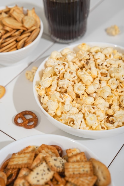 Golosità fatte in casa fast food una ciotola con cracker di popcorn e biscotti su un tavolo bianco