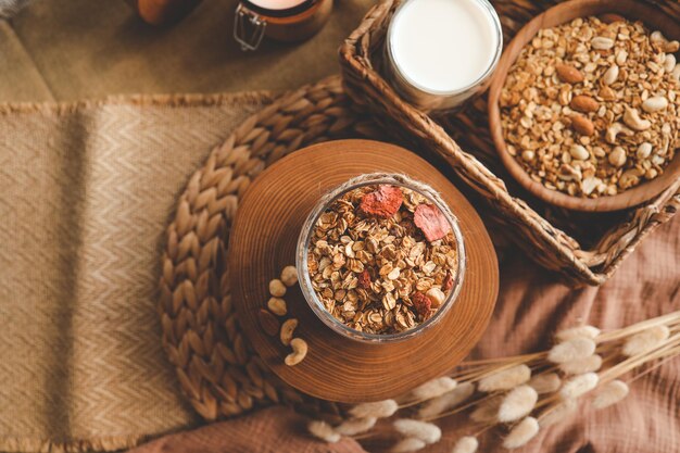 Homemade granola in a glass jar against the background of milk candle and decor good morning concept