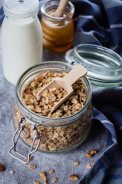 Homemade granola in glass jar on gray stone table. Ingredients for healthy breakfast