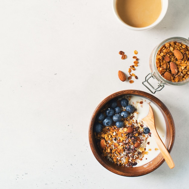 Homemade granola muesli with blueberries and coffee on white, top view