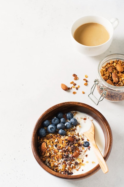 Photo homemade granola muesli with blueberries and coffee on white, vertical top view