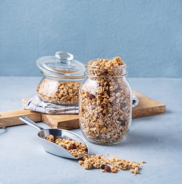 Granola casalingo con le noci in un barattolo di vetro su fondo blu spuntino sano del vegano