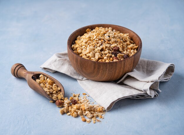 Granola casalingo con le noci in ciotola di legno su fondo blu alimento sano del vegano