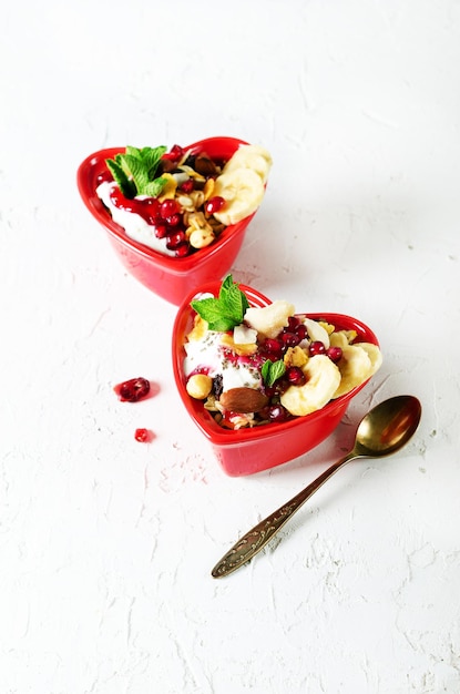 Homemade granola with yogurt in red heart plate on white table Romantic breakfast Free space for your text