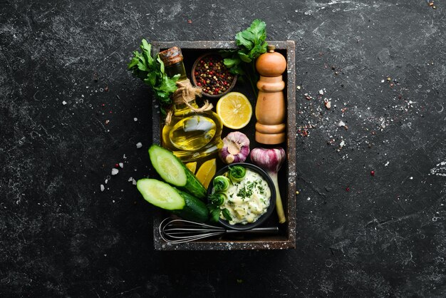 Homemade Greek sauce with cucumber lemon and garlic on a black background Top view Free space for your text