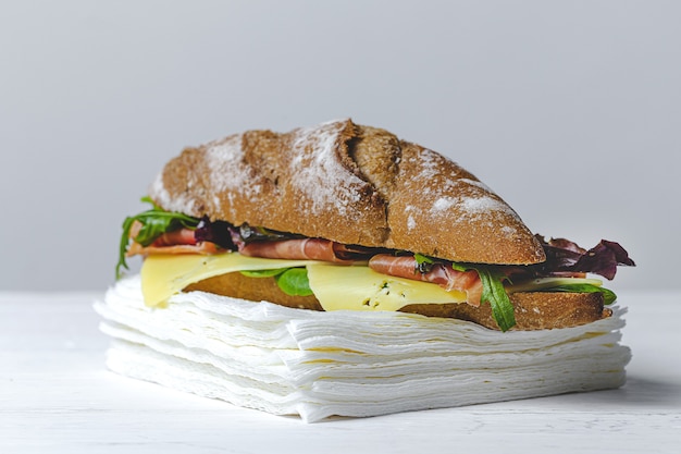 Panino al prosciutto fatto in casa con rucola, lattuga e formaggio con pane ai semi. porta via. consegna di cibo