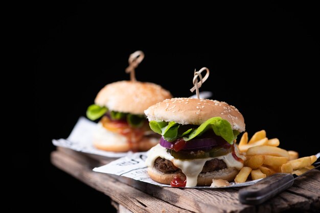 Homemade hamburger or burger with french fries on wooden table Close up