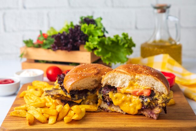 Homemade hamburger served with french fries. It looks delicious prepared with onions, hamburger patties, cheddar cheese and ham.