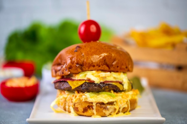 Homemade hamburger served with french fries. It looks delicious prepared with onions, hamburger patties, cheddar cheese and ham.