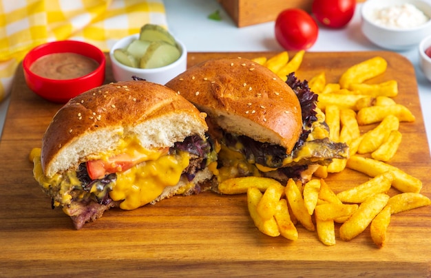 Homemade hamburger served with french fries. It looks delicious prepared with onions, hamburger patties, cheddar cheese and ham.