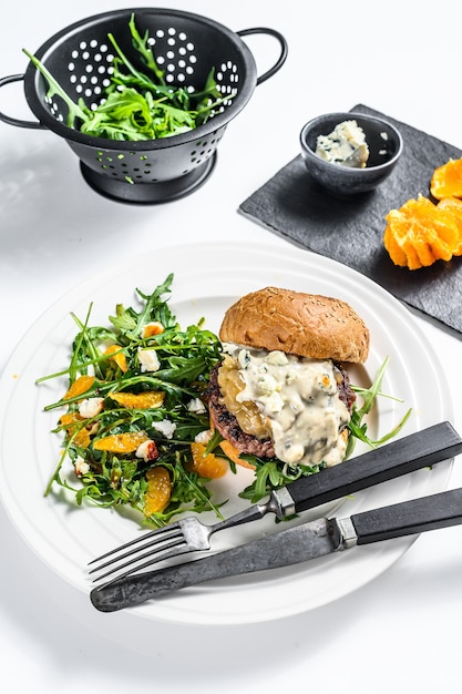 Homemade  hamburger with blue cheese, marbled beef and onion marmalade, a side dish of salad with arugula and oranges