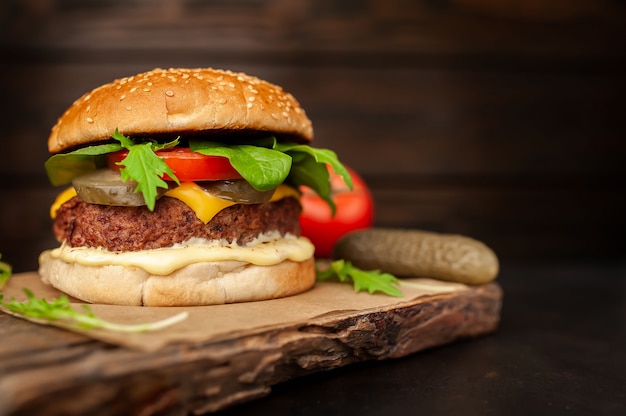 Hamburger fatti in casa con lattuga, pomodoro, formaggio e cetriolo su un tagliere