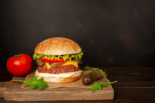 Домашний гамбургер с салатом, помидорами, сыром и огурцом на разделочной доске