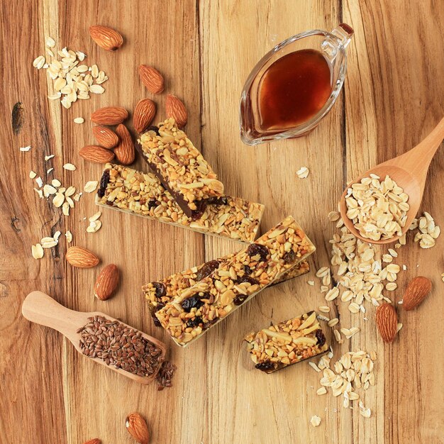 Homemade healthy cereal bars with granola, nuts, and dried\
fruits on brown retro background, top view. noise from table\
texture