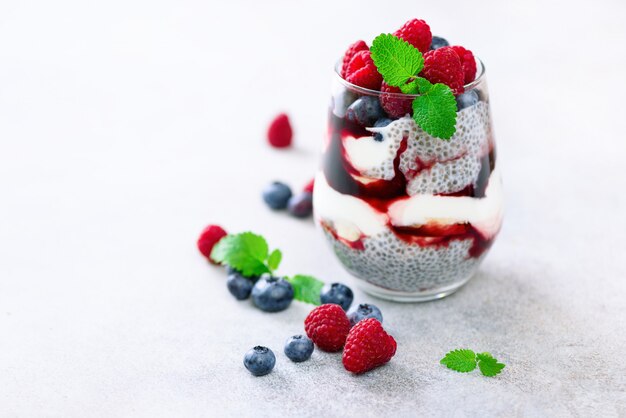 Budino sano fatto in casa di chia, bacche, lamponi, mirtilli, menta, latte di mandorla in un bicchiere.