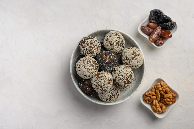 Homemade healthy energy balls made from fruits, nuts, cocoa, honey in a light vase. Next to the vases with dates and walnuts. Copy space. Top view