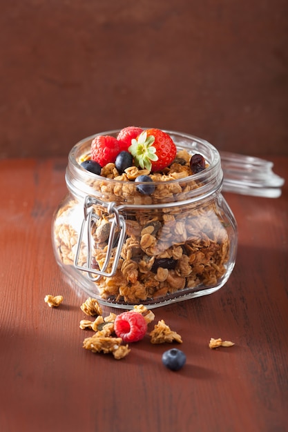 Homemade healthy granola in glass jar and berries