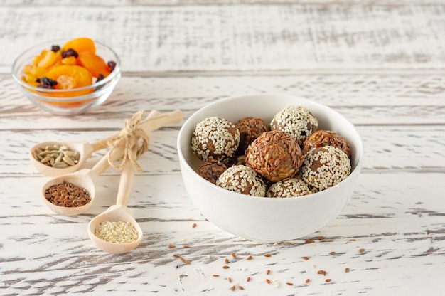 Homemade Healthy Paleo Raw Energy Balls with Nuts, coconut flakes and Dates on a white plate with ingridients.