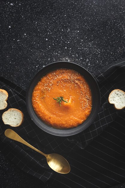 Homemade and healthy pumpkin cream with bread from above on  dark background